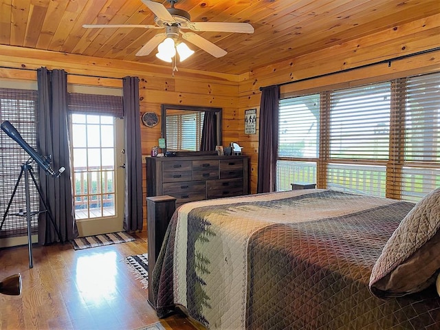 bedroom with ceiling fan, wood finished floors, wooden walls, and wooden ceiling