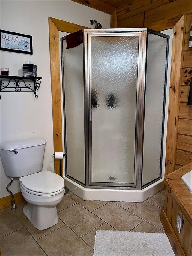 bathroom with tile patterned floors, toilet, and a shower stall