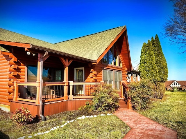 view of home's exterior with covered porch, log exterior, and a shingled roof