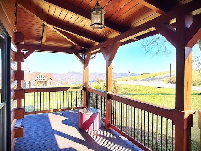 wooden deck with a mountain view and a yard