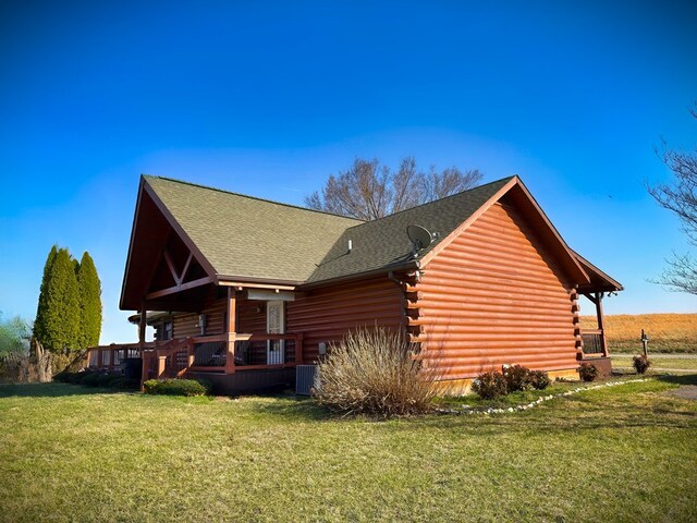 view of property exterior featuring log exterior, central AC unit, a yard, and roof with shingles