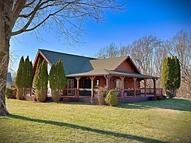 view of front of home featuring log siding, covered porch, a shingled roof, and a front yard