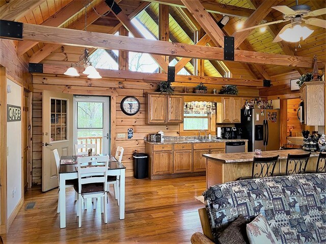 kitchen with wooden walls, beam ceiling, light wood-style flooring, appliances with stainless steel finishes, and brown cabinets