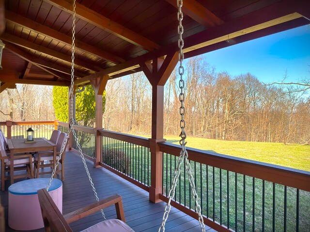 wooden deck with a lawn and a forest view