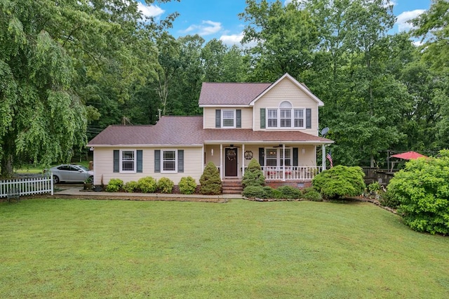 view of front of property featuring covered porch, roof with shingles, a front yard, and fence