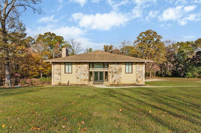 view of front of house featuring stone siding, a chimney, a front lawn, and french doors