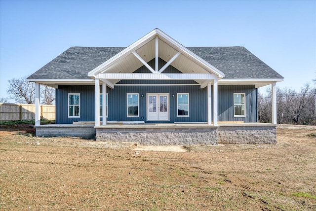 back of house featuring a porch, a lawn, and roof with shingles