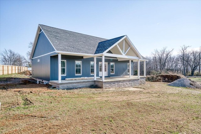 view of front of property featuring a porch, a shingled roof, a front lawn, and fence