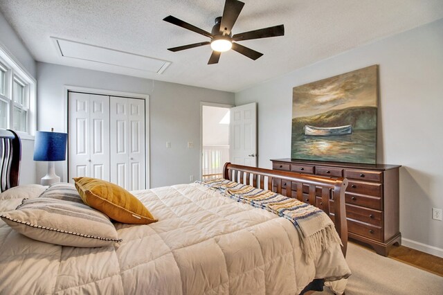 bedroom with a textured ceiling, a ceiling fan, baseboards, a closet, and attic access