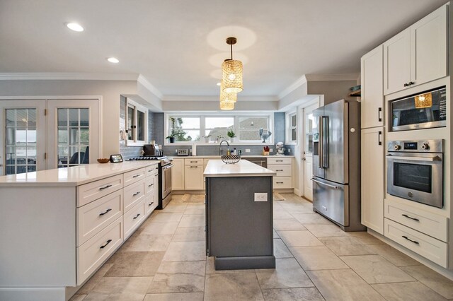 kitchen with pendant lighting, light countertops, appliances with stainless steel finishes, white cabinetry, and a kitchen island