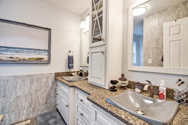 bathroom with double vanity, a sink, and tile walls