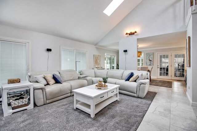 living room with a skylight, marble finish floor, and high vaulted ceiling