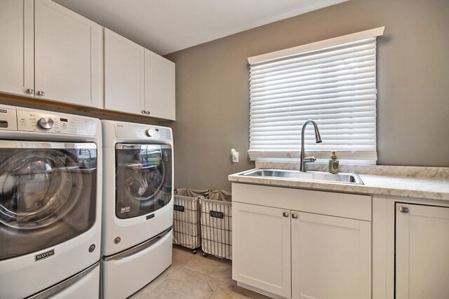 laundry area with washing machine and clothes dryer, a sink, and cabinet space