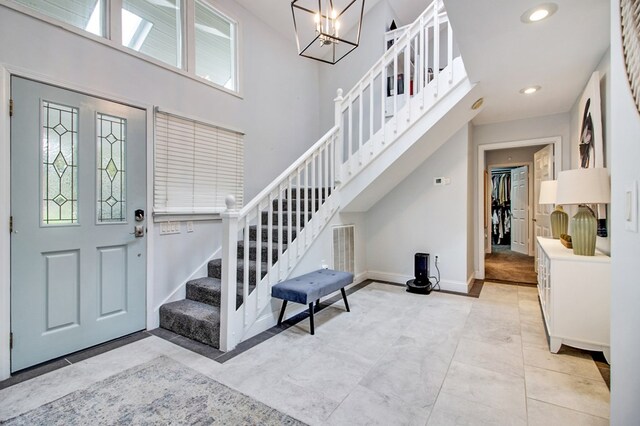 foyer entrance featuring recessed lighting, stairway, a high ceiling, an inviting chandelier, and baseboards