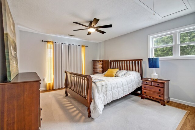 bedroom featuring attic access, visible vents, baseboards, ceiling fan, and a textured ceiling