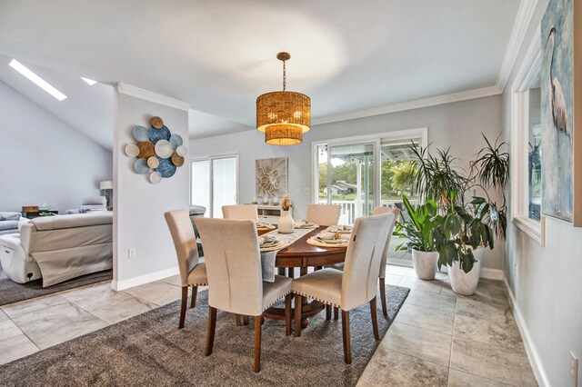 dining room featuring lofted ceiling with skylight, crown molding, and baseboards