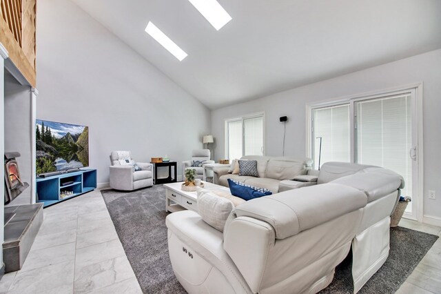 living room featuring high vaulted ceiling and a skylight