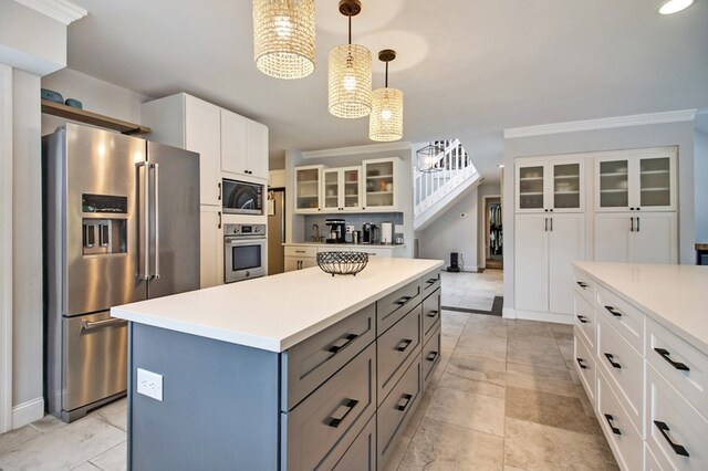 kitchen with decorative light fixtures, stainless steel appliances, white cabinets, light countertops, and glass insert cabinets