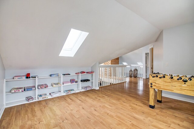 rec room with vaulted ceiling with skylight and wood finished floors