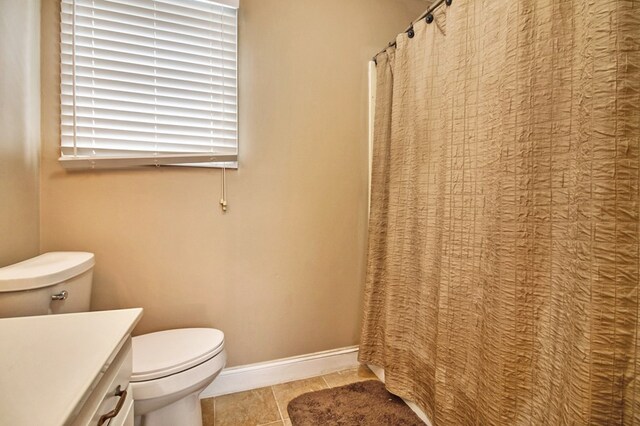 full bath with toilet, tile patterned flooring, baseboards, and vanity