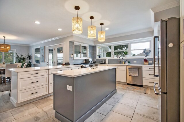 kitchen with hanging light fixtures, a kitchen island, appliances with stainless steel finishes, and light countertops