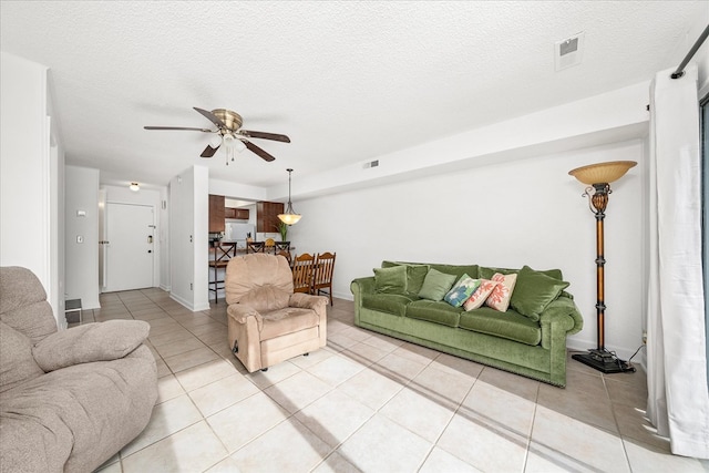 living area with a textured ceiling, visible vents, light tile patterned flooring, and a ceiling fan