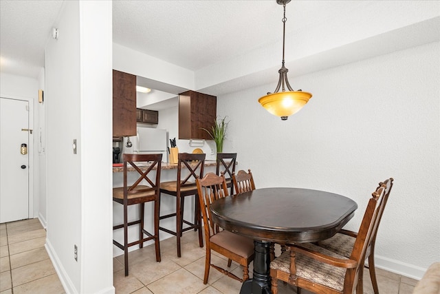 dining room featuring light tile patterned floors, baseboards, and a textured ceiling