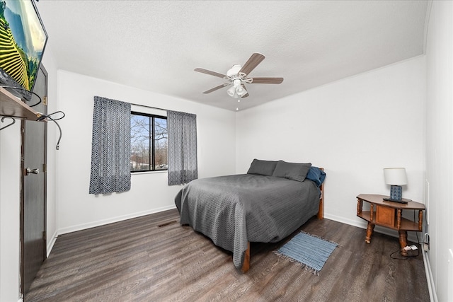 bedroom featuring dark wood finished floors, a textured ceiling, and baseboards