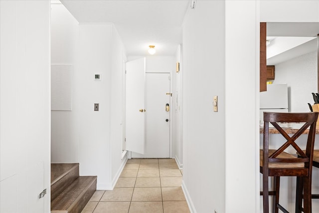 hallway with stairs, baseboards, and light tile patterned floors