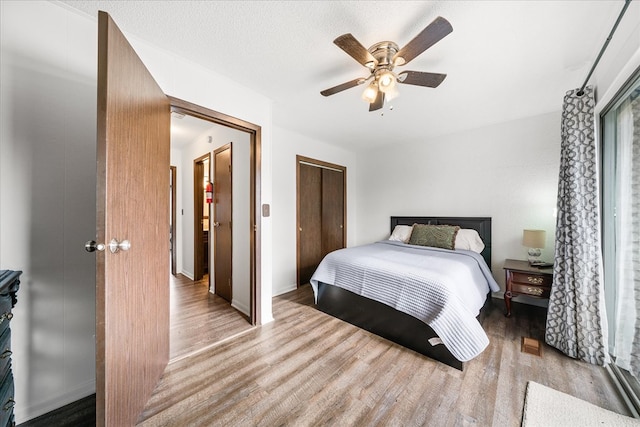 bedroom with a textured ceiling, light wood finished floors, a closet, and a ceiling fan