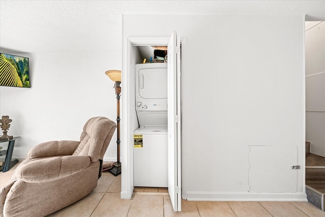 laundry room featuring stacked washer and dryer, laundry area, a textured ceiling, and light tile patterned floors