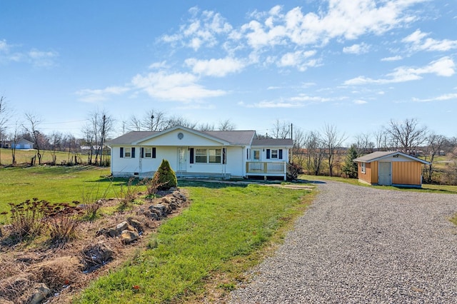 view of front of property featuring covered porch, driveway, a front yard, and an outdoor structure