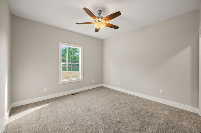 carpeted spare room with baseboards, visible vents, and a ceiling fan