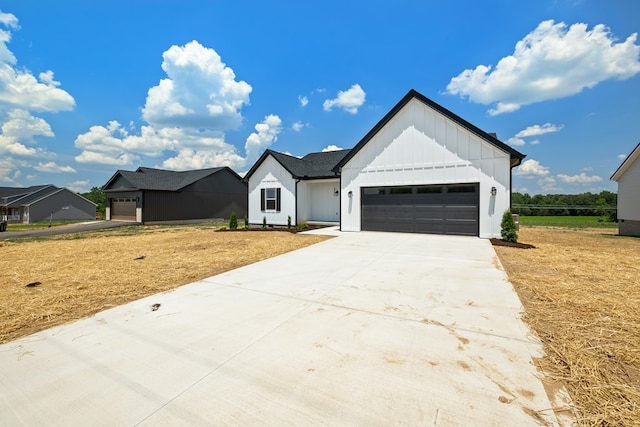 modern farmhouse with an attached garage, driveway, board and batten siding, and a front yard