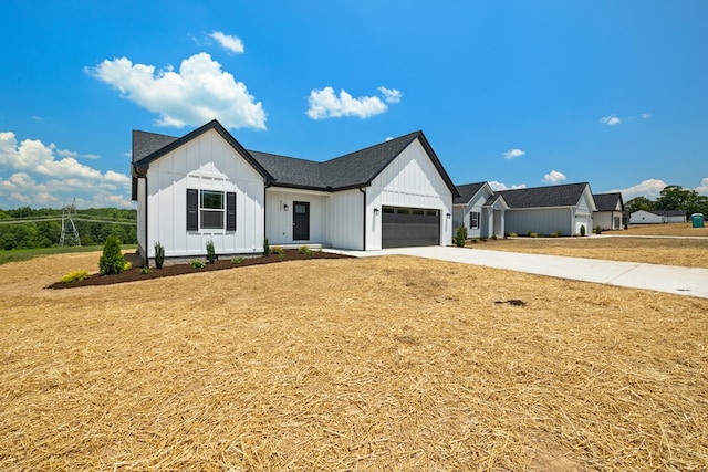 modern inspired farmhouse featuring roof with shingles, concrete driveway, board and batten siding, a garage, and a front lawn