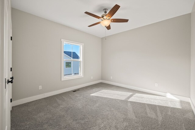 carpeted spare room featuring a ceiling fan, visible vents, and baseboards