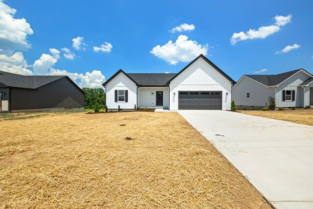 modern farmhouse style home with an attached garage, driveway, board and batten siding, and a front yard