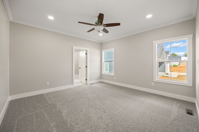 carpeted empty room with ornamental molding, a healthy amount of sunlight, visible vents, and baseboards