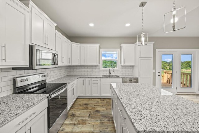 kitchen featuring a sink, white cabinetry, appliances with stainless steel finishes, backsplash, and pendant lighting