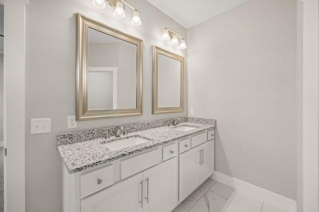 bathroom with marble finish floor, a sink, baseboards, and double vanity