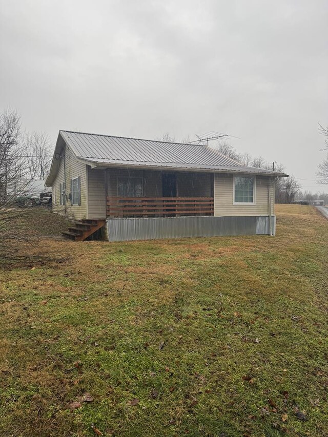 exterior space with metal roof and a lawn