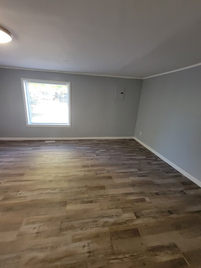 unfurnished room with baseboards, dark wood-type flooring, and crown molding