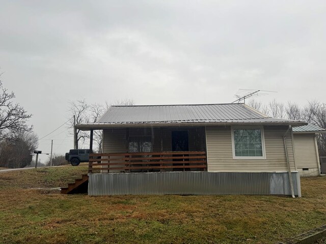 rear view of house featuring crawl space, metal roof, and a lawn