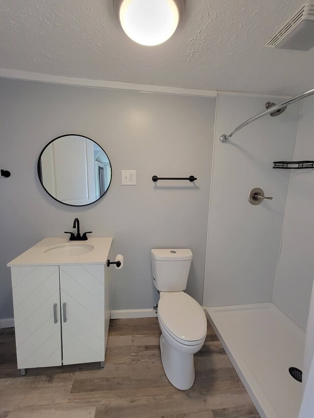 bathroom with a textured ceiling, visible vents, wood finished floors, and vanity