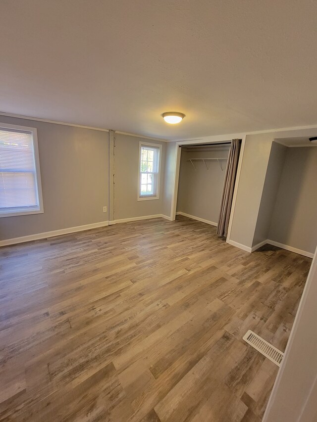 unfurnished bedroom with wood finished floors, visible vents, and baseboards