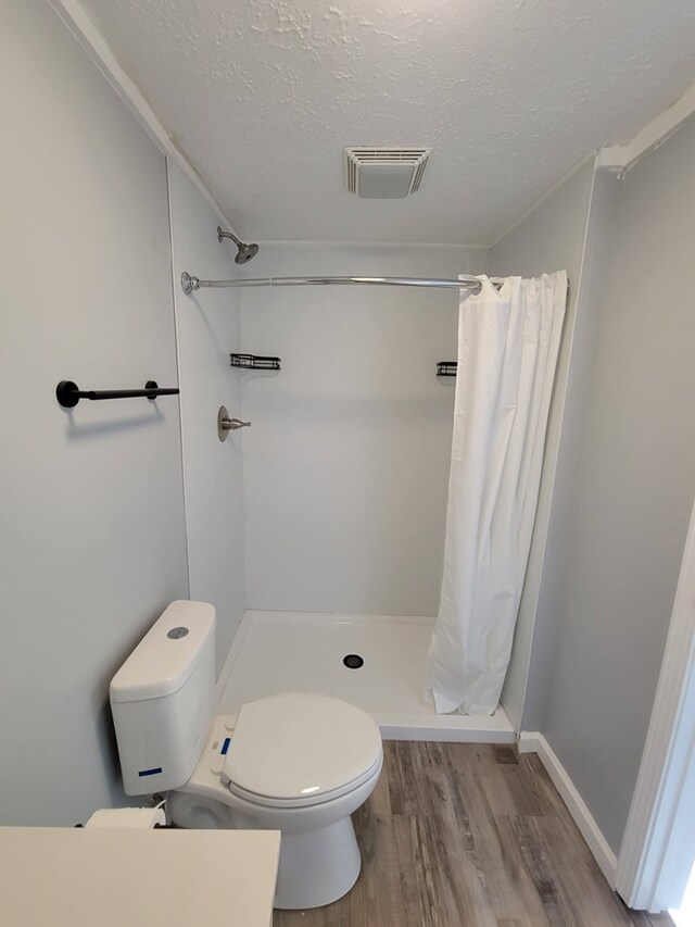 bathroom with toilet, a stall shower, visible vents, and wood finished floors