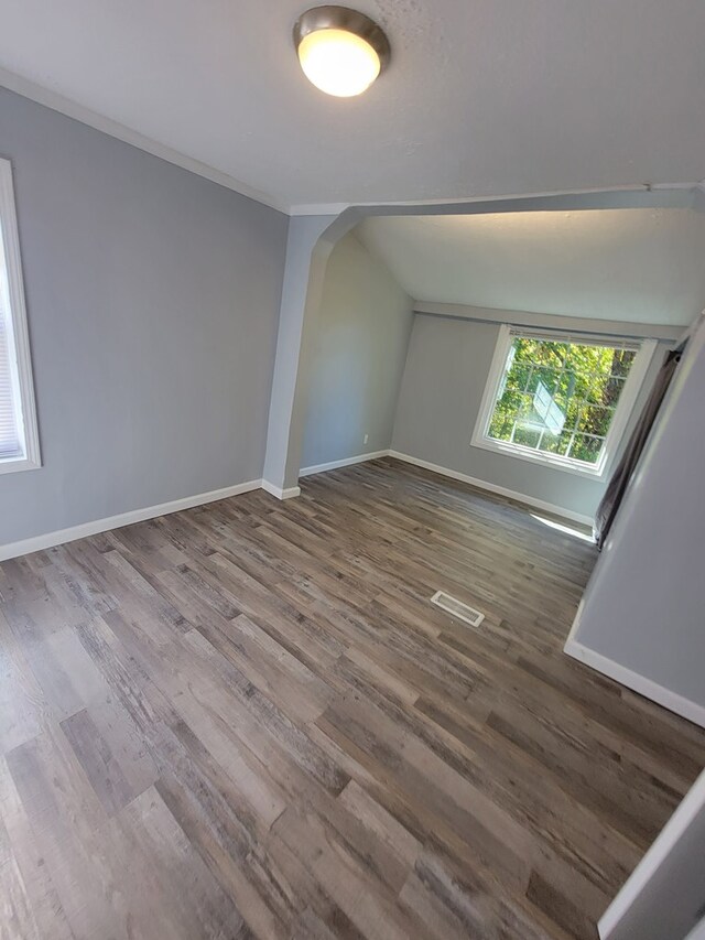 bonus room featuring arched walkways, dark wood-type flooring, visible vents, baseboards, and vaulted ceiling