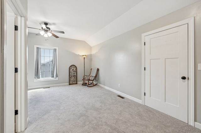 unfurnished room featuring baseboards, visible vents, vaulted ceiling, and carpet flooring