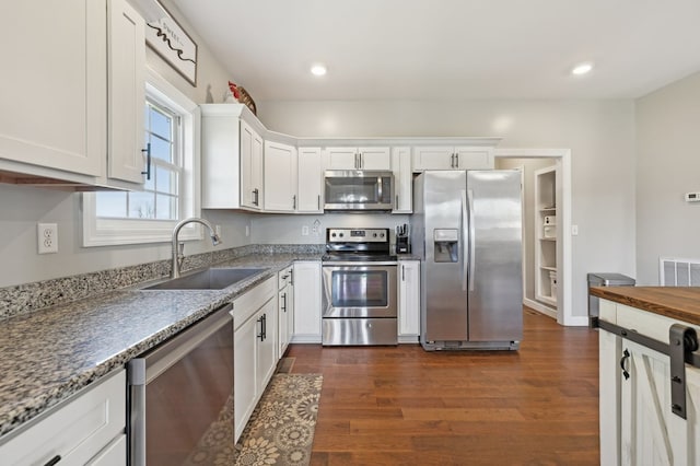 kitchen featuring recessed lighting, stainless steel appliances, dark wood-type flooring, a sink, and white cabinets