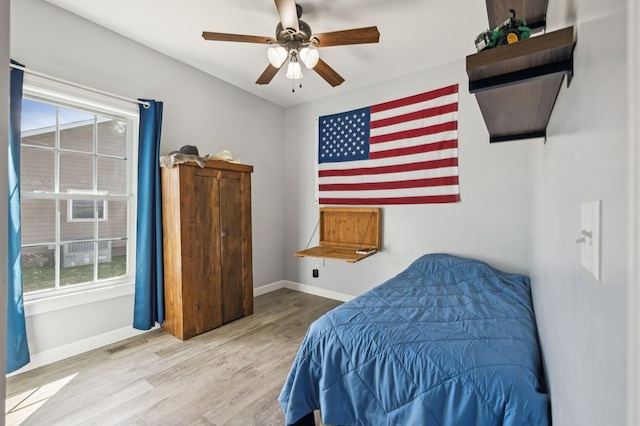 bedroom with ceiling fan, wood finished floors, visible vents, and baseboards